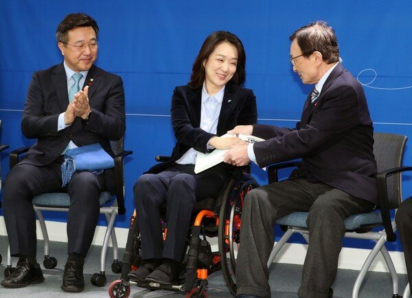 이해찬 더불어민주당 대표가 26일 서울 여의도 더불어민주당 중앙당사에서 21대 총선 인재영입 1호인 발레리나 출신 척수장애인 최혜영 교수에게 민주당 당헌 당규집을 전달하고 있다. 2019.12.26./뉴스1